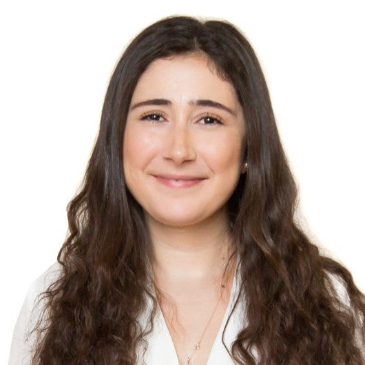 Woman with long dark hair wearing a white shirt on a plain background
