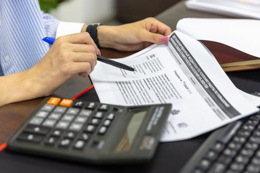 Person reviewing financial documents with a calculator at a desk